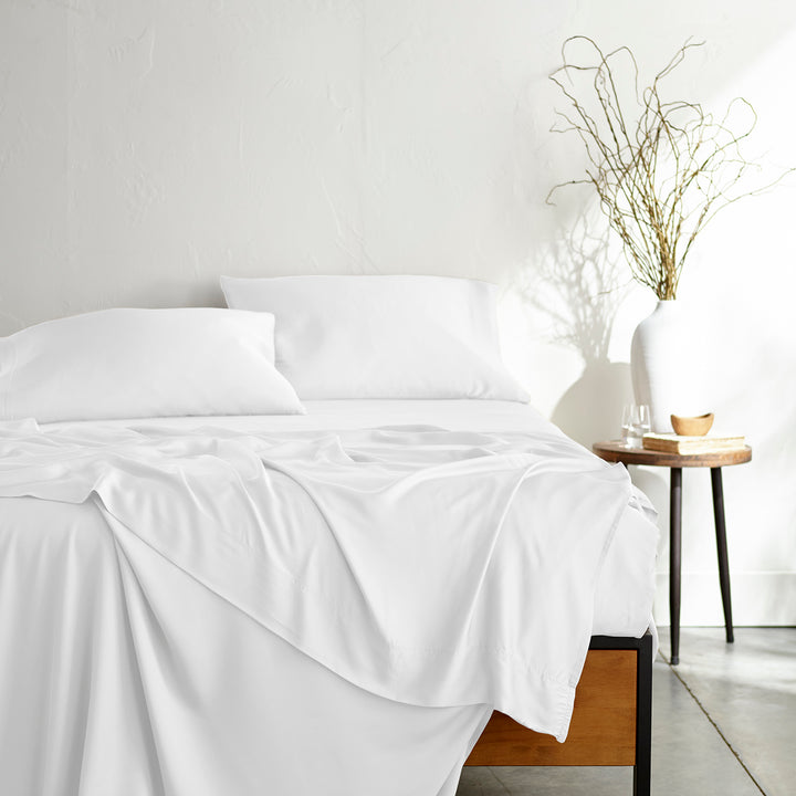 white bamboo bed sheets with sateen weave from the Signature Collection, shown from the foot of the bed with a draped flat sheet and matching pillowcases