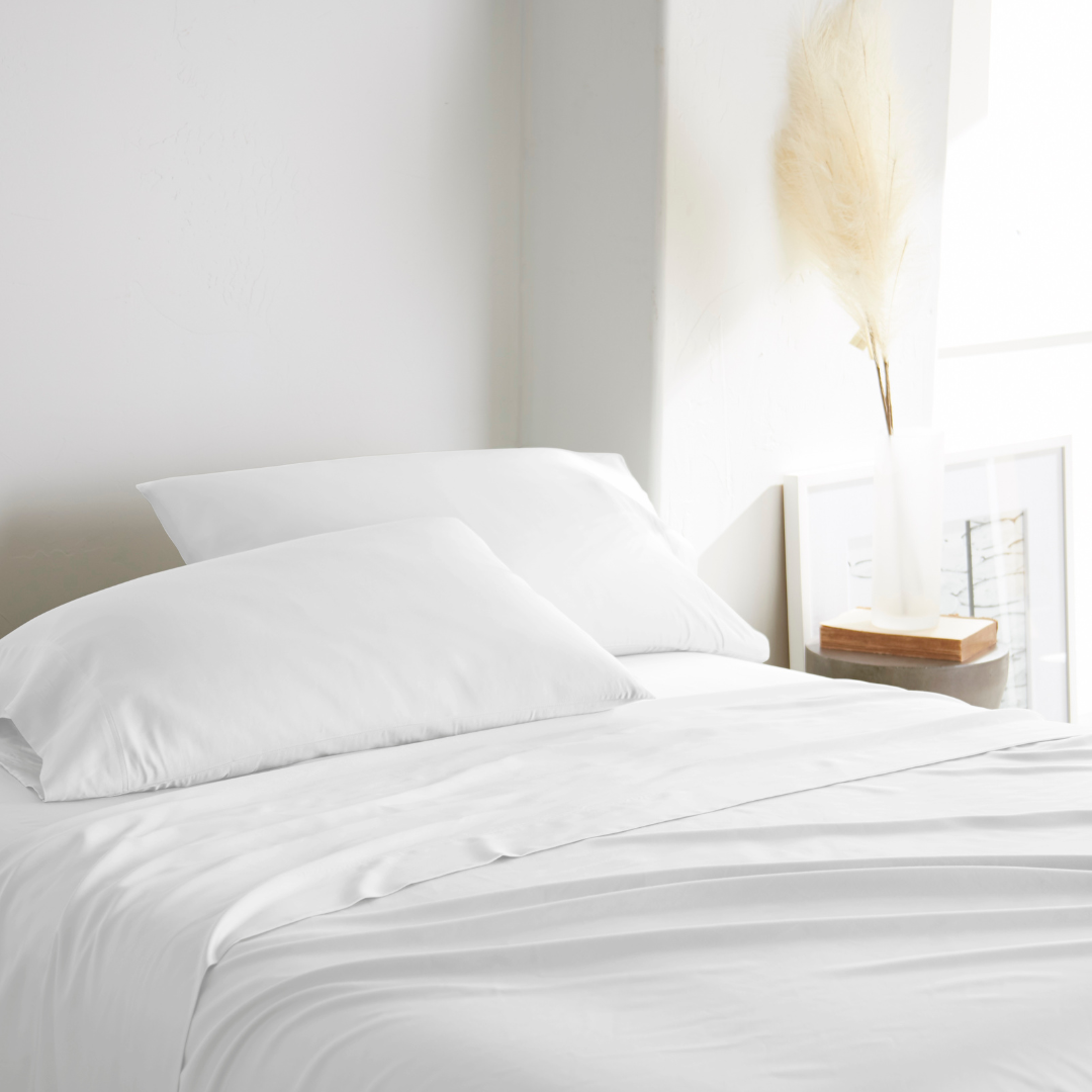 white bamboo bed sheets with sateen weave from the Premium Collection, three-quarter angle showing natural folds and soft lighting from nearby window